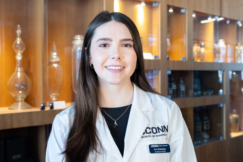 A girl with long brown hair in a white coat posing for a photo
