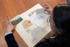A woman looks at artwork on a table.