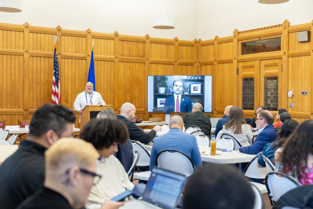 People sitting at tables listening to a speaker at a podium