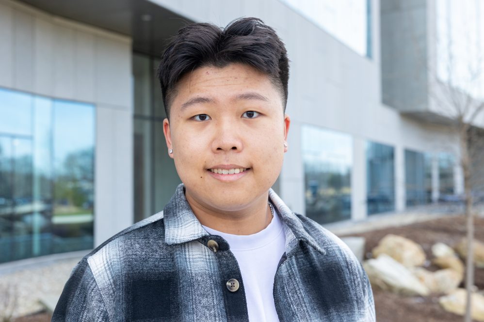 A man posing for a portrait outside of a building in a flannel shirt