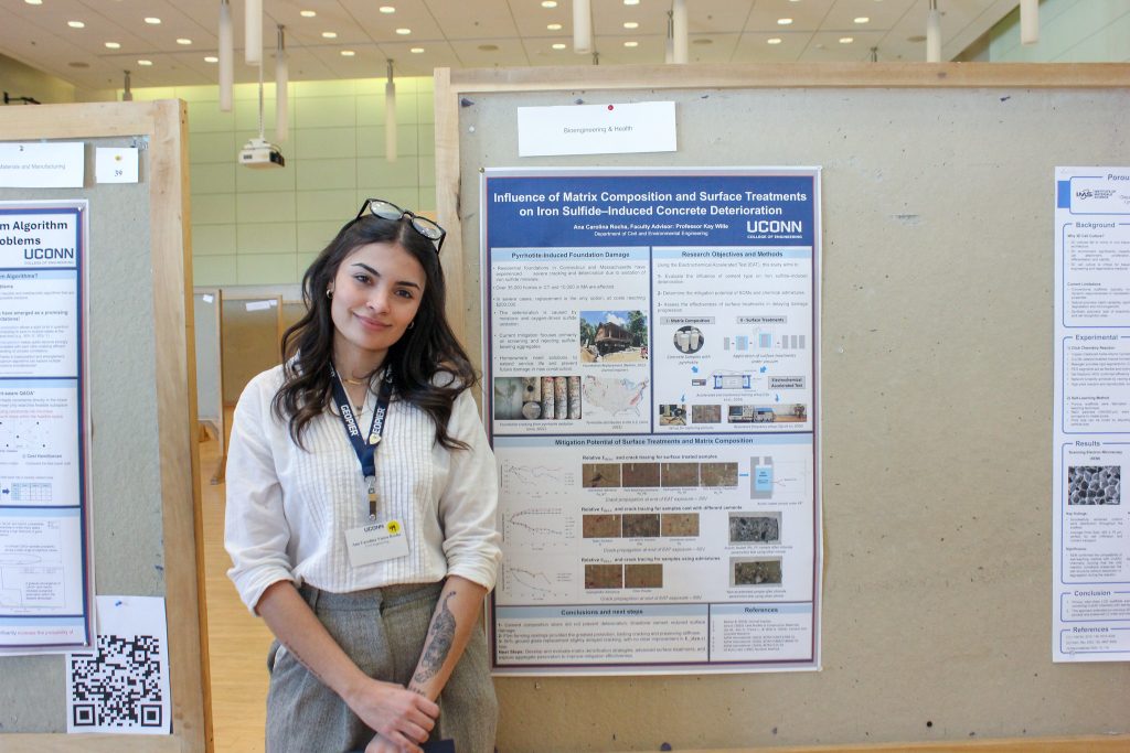 Ana Carolina Vieira Rocha, Civil Engineering graduate student, stands beside her research poster at the UConn Engineering Graduate Poster Competition.