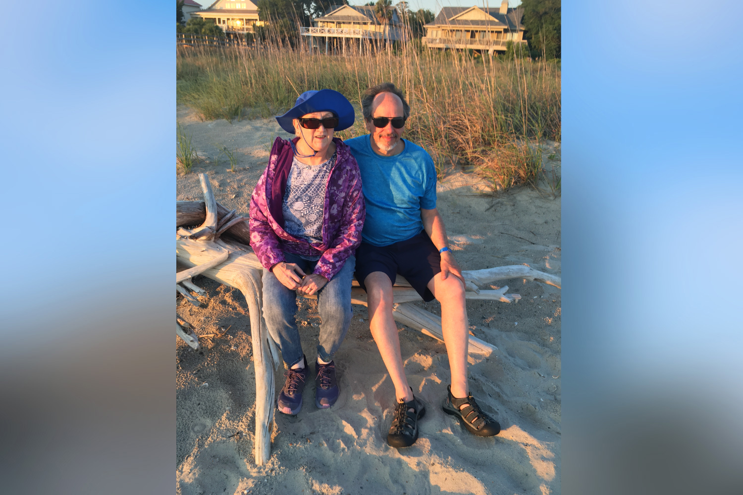 A woman and a man sitting on a rock at the beach