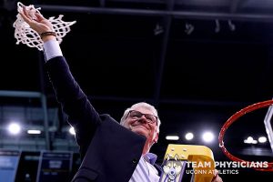 coach holds up net he just cut down from basketball hoop