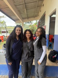 Three young women pose for a portrait photograph in a health clinic.