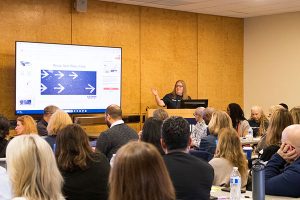 woman presenting to a conference room from podium