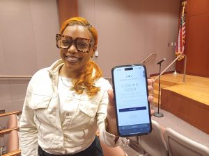 A woman holding up a phone screen showing us an app