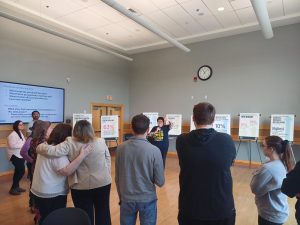 A person talking in front of a group of people in front of larger posters