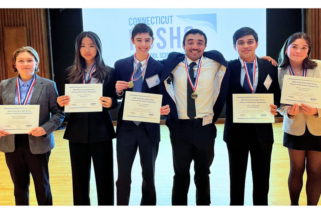 group portrait six students holding awards on stage