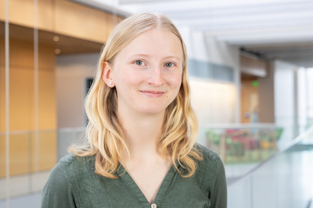 A woman with blonde hair poses for a phot inside a building