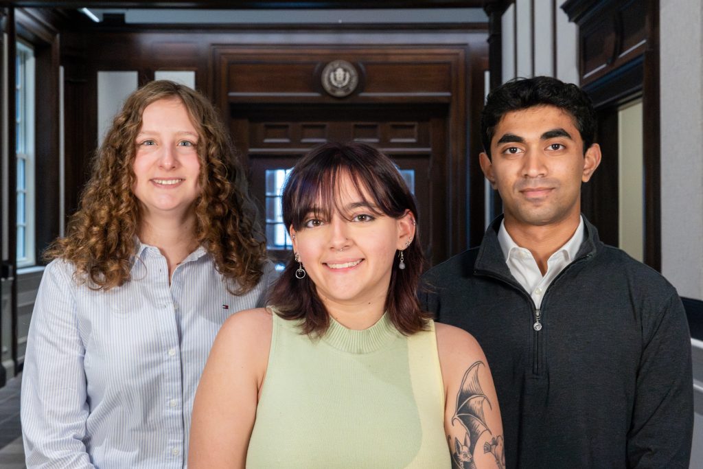 Three students posing for a photo inside a building