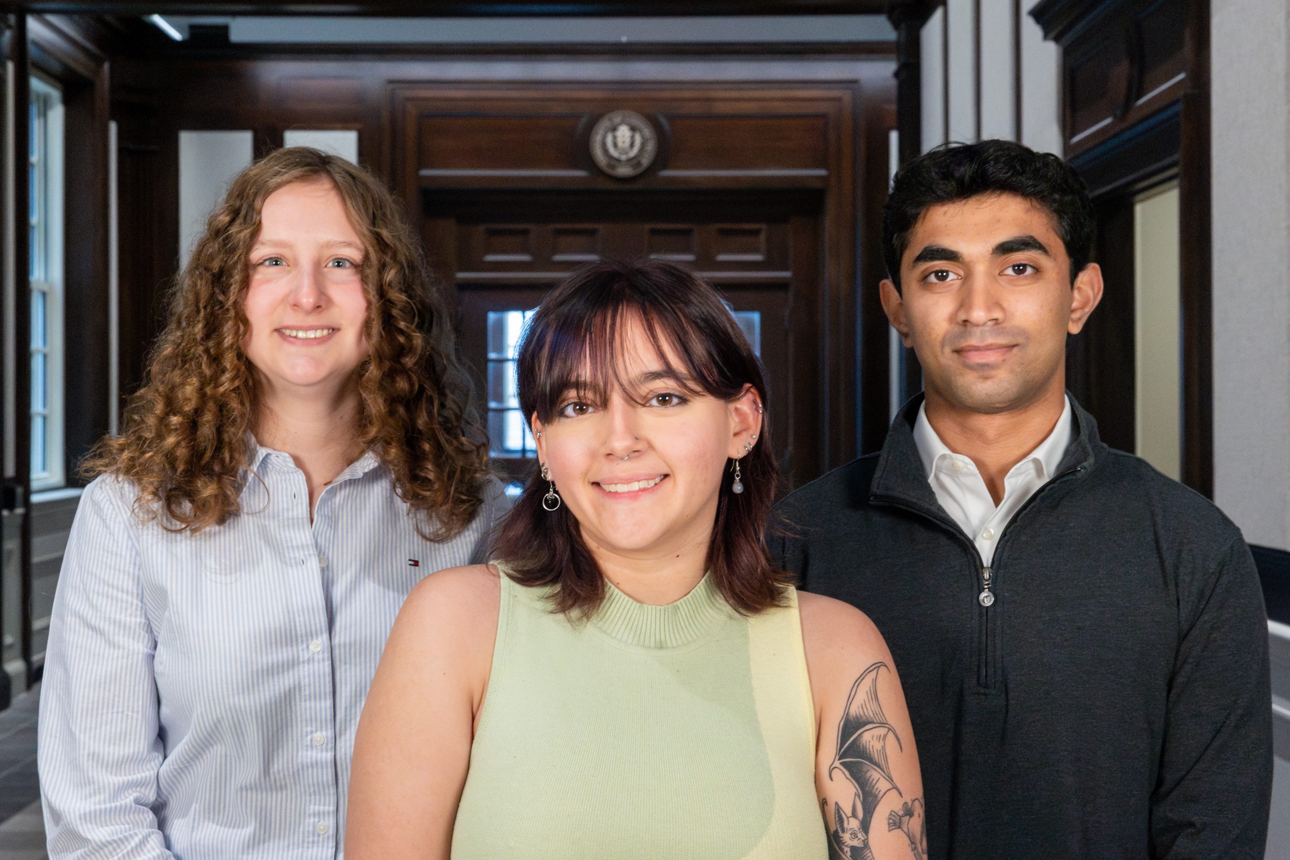 Three students posing for a photo inside a building