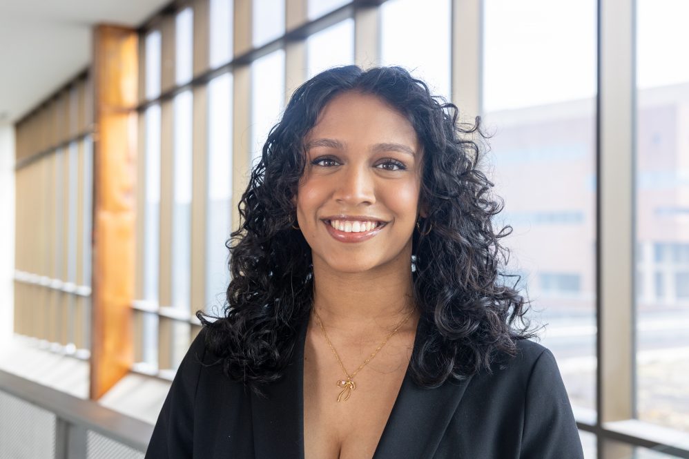 A woman with curly black hair poses for a photo