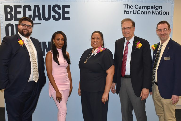 Four alumni award recipients pose with the dean of the College of Liberal Arts and Sciences in front of a UConn Foundation campaign backdrop.