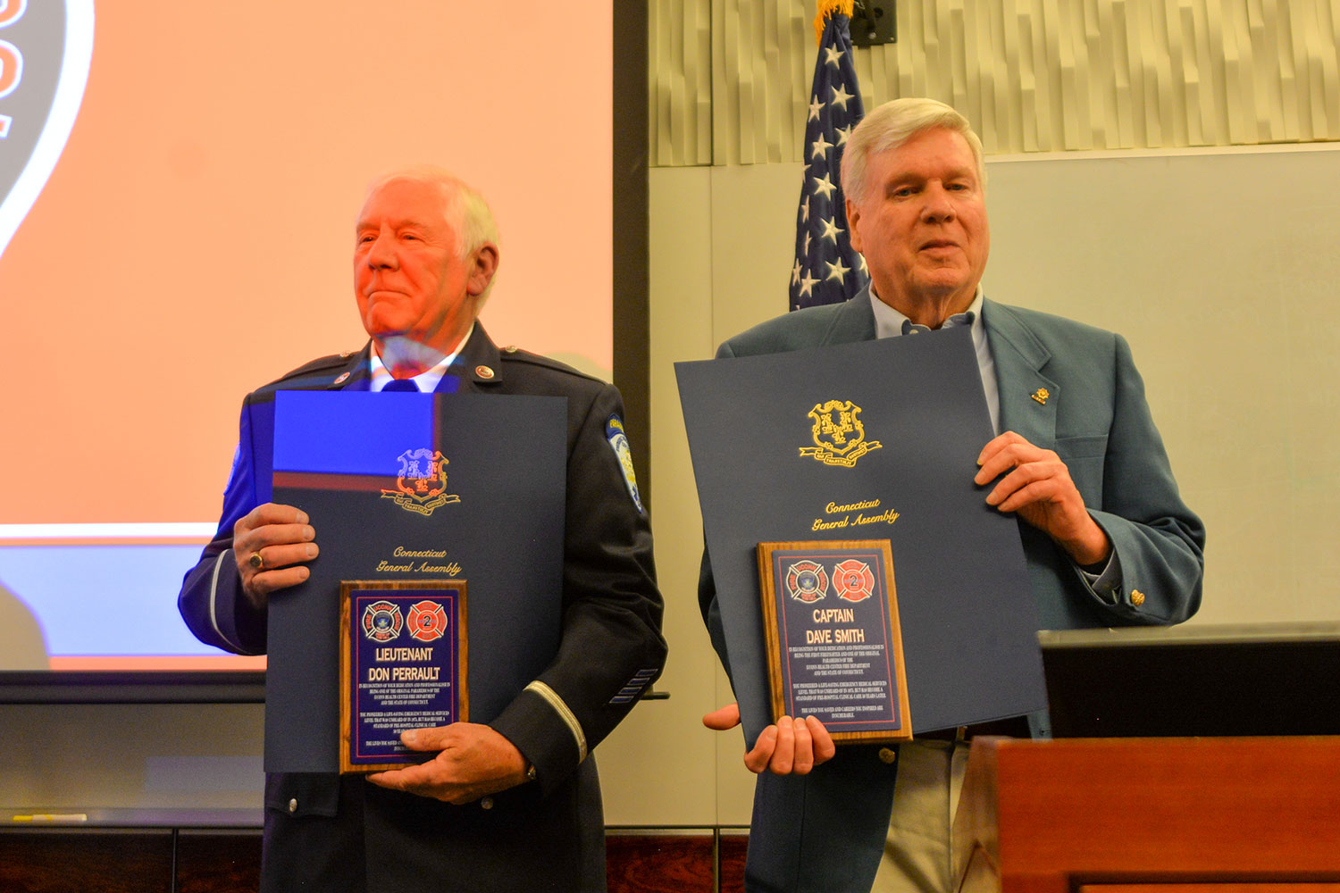 Portrait two retired firefighter paramedics holding plaques and citations