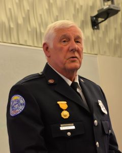 Retired Fire Lt. Don Perreault in dress uniform speaking at podium