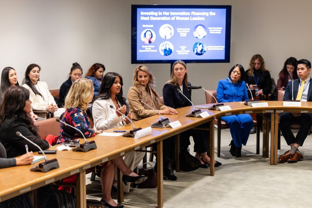Five women sitting at a table talking into microphones