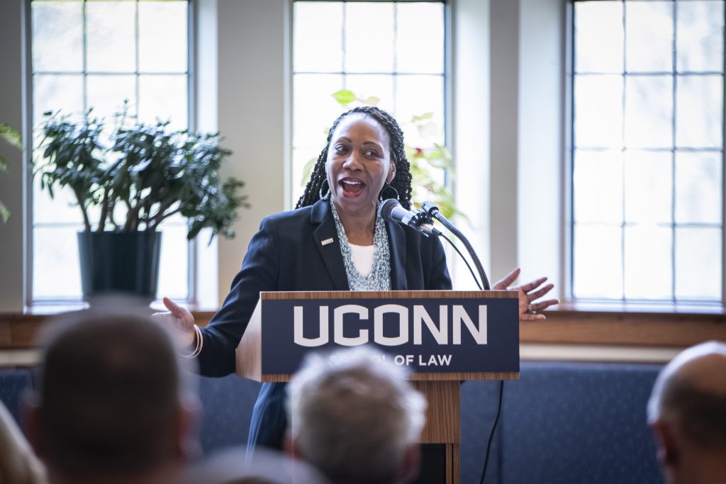A woman stands at a podium with a UConn sign on it.