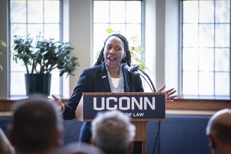 A woman stands at a podium with a UConn sign on it.
