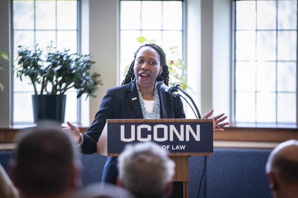 A woman stands at a podium with a UConn sign on it.