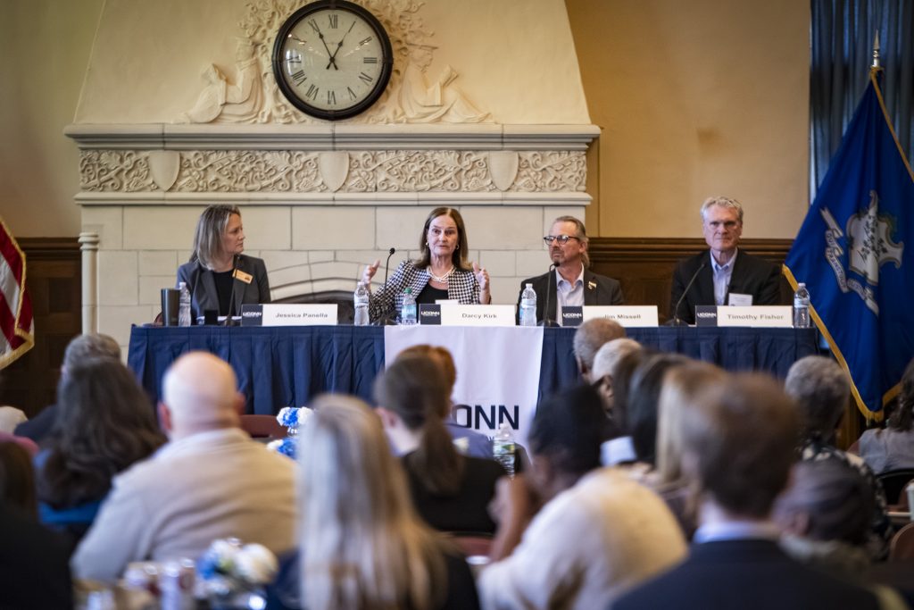 Four people sit at a table at the head of a crowded room.
