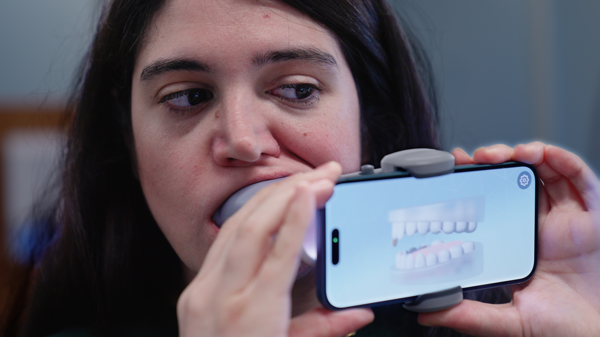 A mock patient demonstrates using a scan box and her cell phone how AI is being used in orthodontics. (Ryan Bernat/UConn Health)