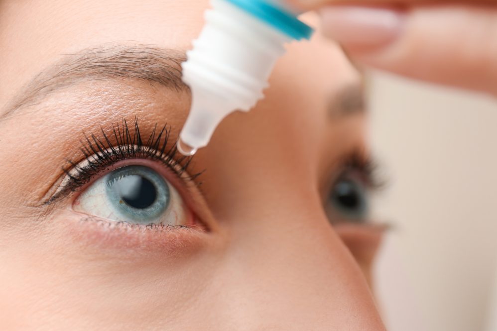Young woman using eye drops.
