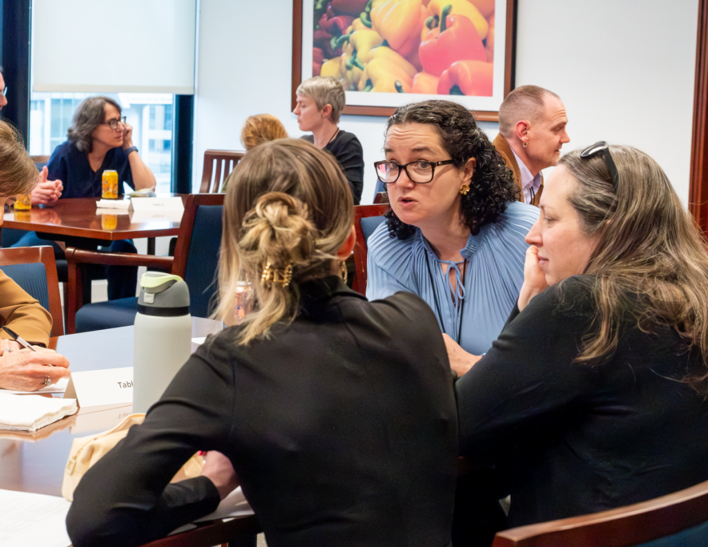 A group of women have an animated conversation at a table.