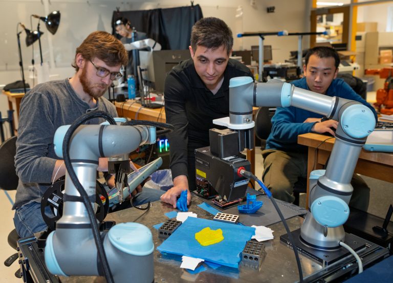 Researchers testing collaborative robotic arms and 3D printing equipment in a lab.
