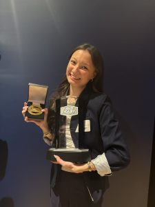 Hailey Dewalt smiling and holding two trophies