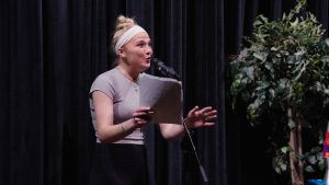 A young girl stands at a microphone performing a story. 
