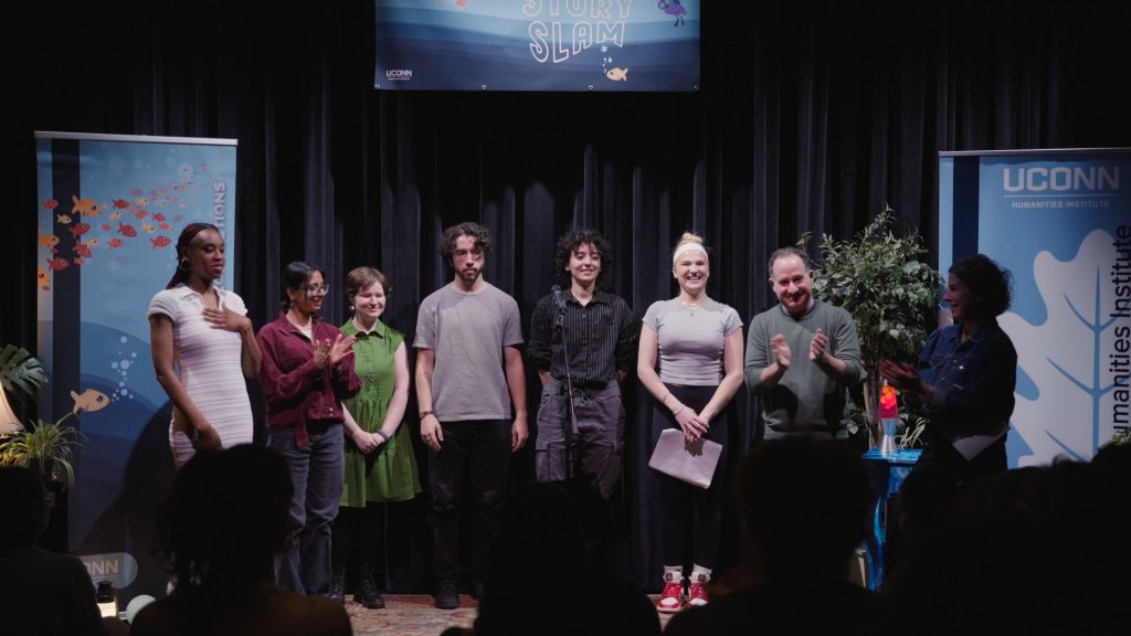 A group of performers stand together at the front of a room.