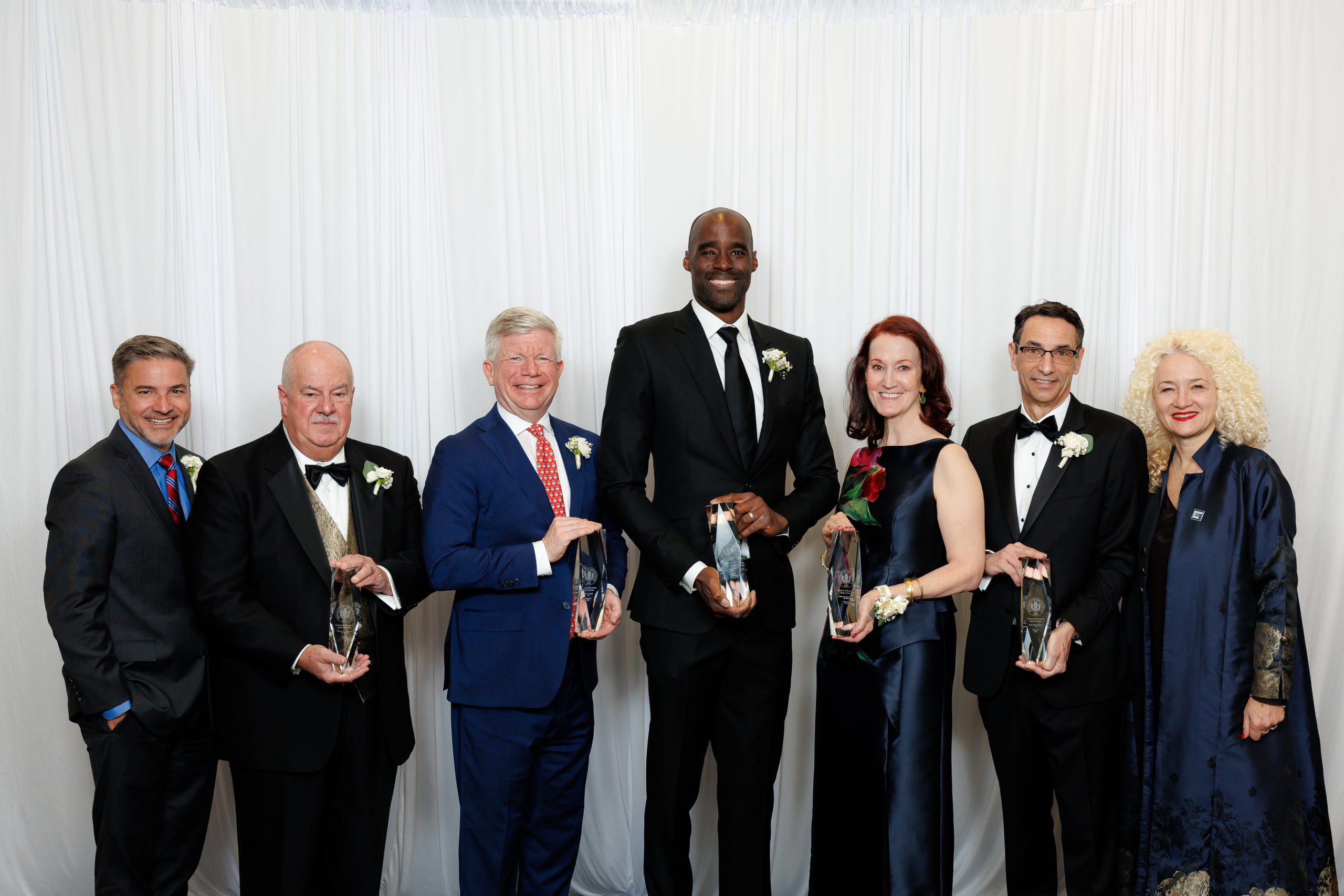 Seven people pose for a photo in dress up attire
