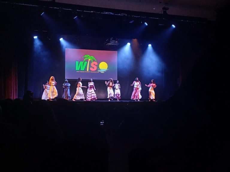 Nine woman on a stage performing with 