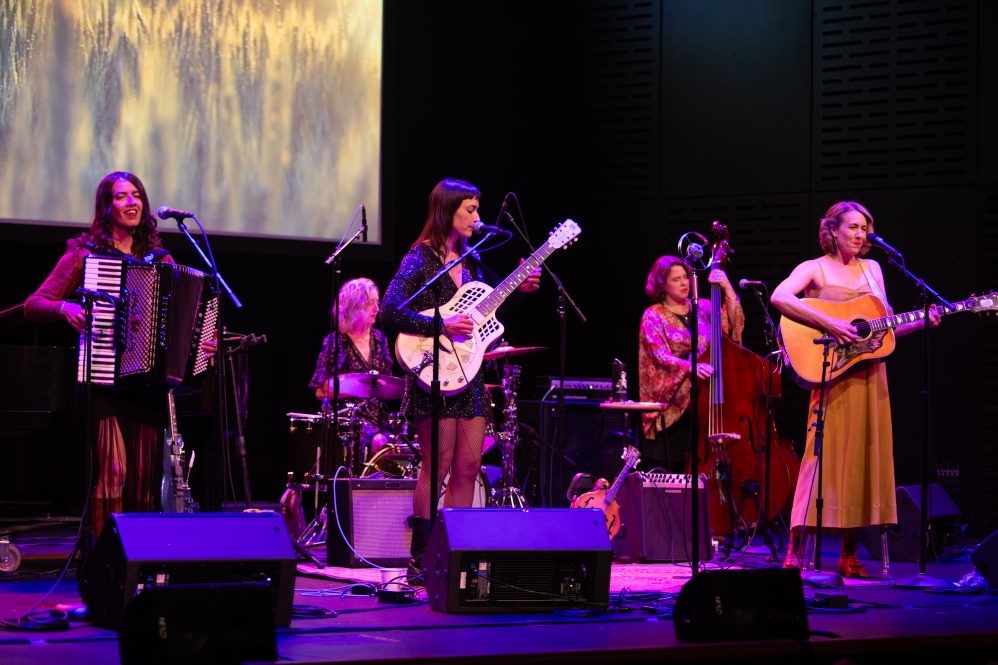 A group of women playing instruments together on stage.