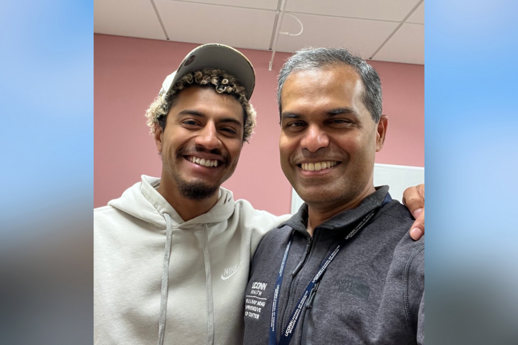 Young man in a baseball cap with his arm around another man both smiling
