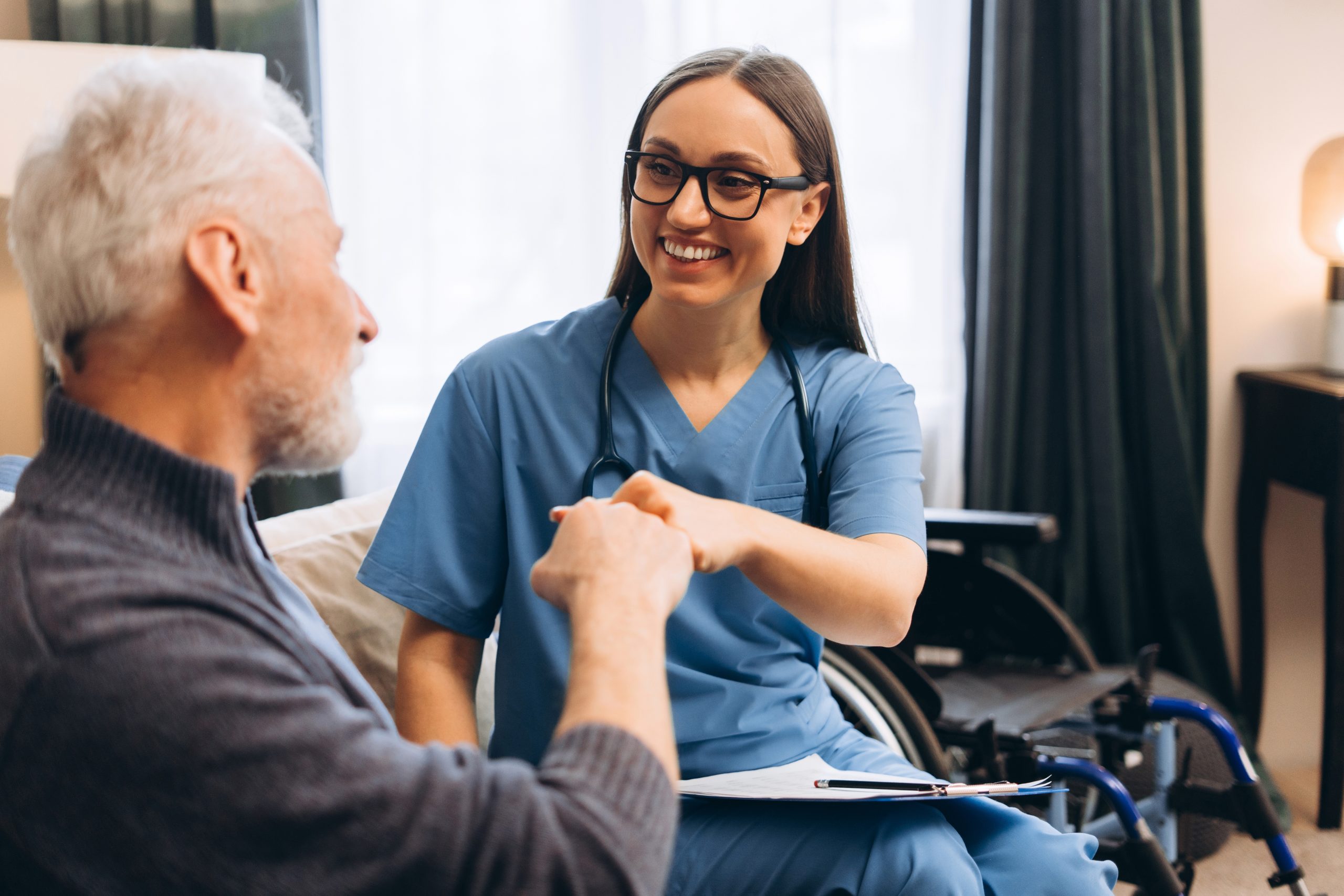 A nurse smiles and fist-bumps an elderly patient