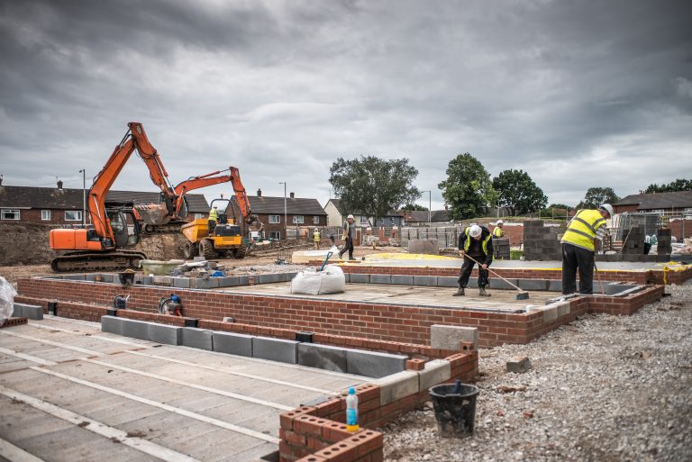 Workers laying bricks on construction site.