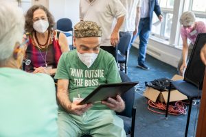 A man in a green t-shirt wearing a medical mask reads a plaque. Archival photo.