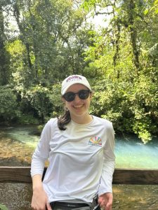 Girl poses in front of water landscape on a school trip.
