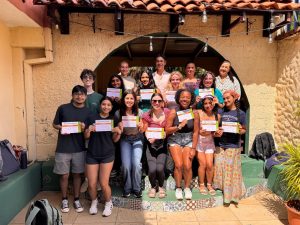 Group of students stand together holding papers on their study abroad trip.