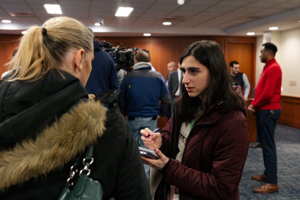 Girl writing notes during an interview while reporting.