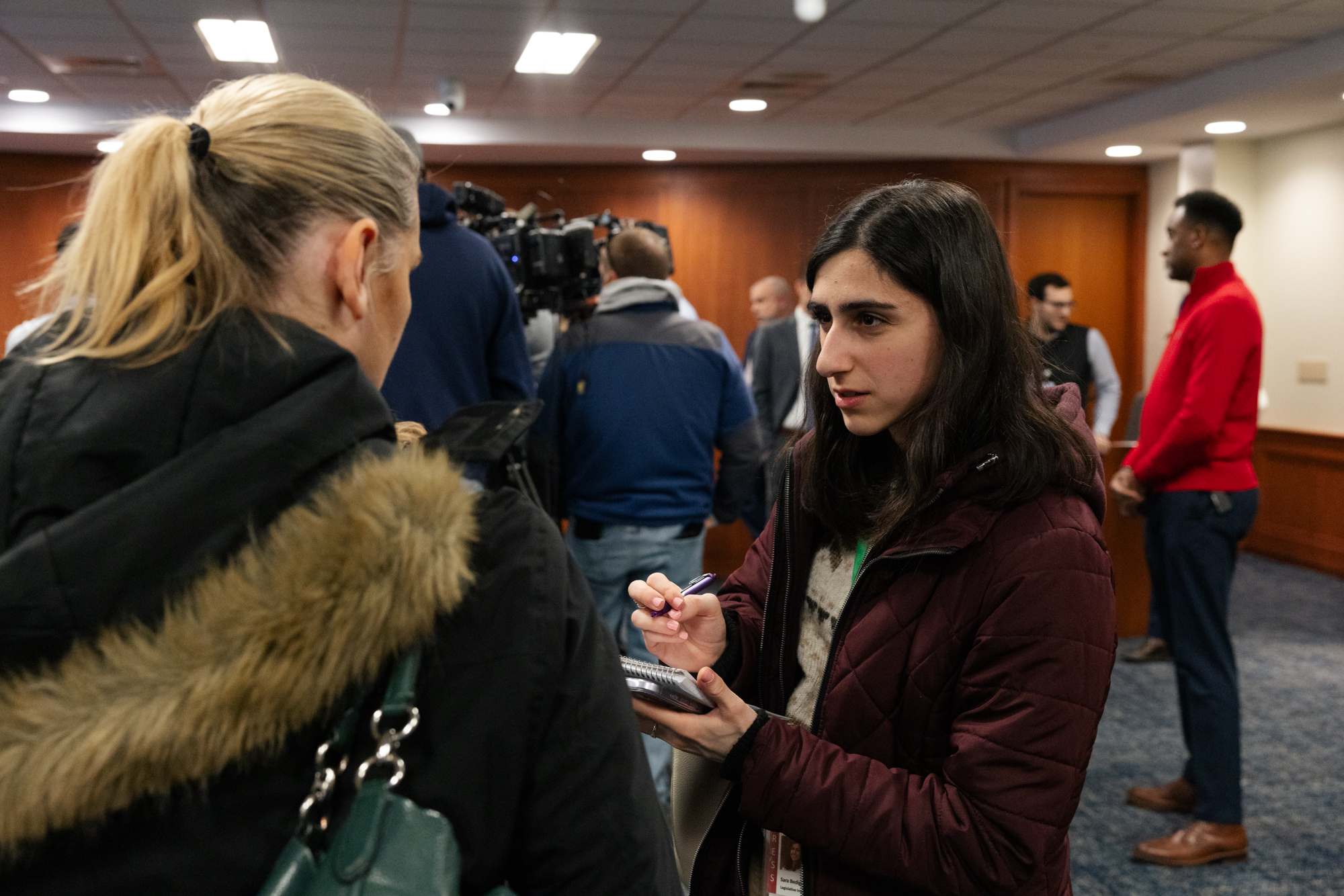 Girl writing notes during an interview while reporting.