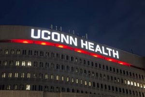 exterior shot of UConn Health at night with building sign lit red