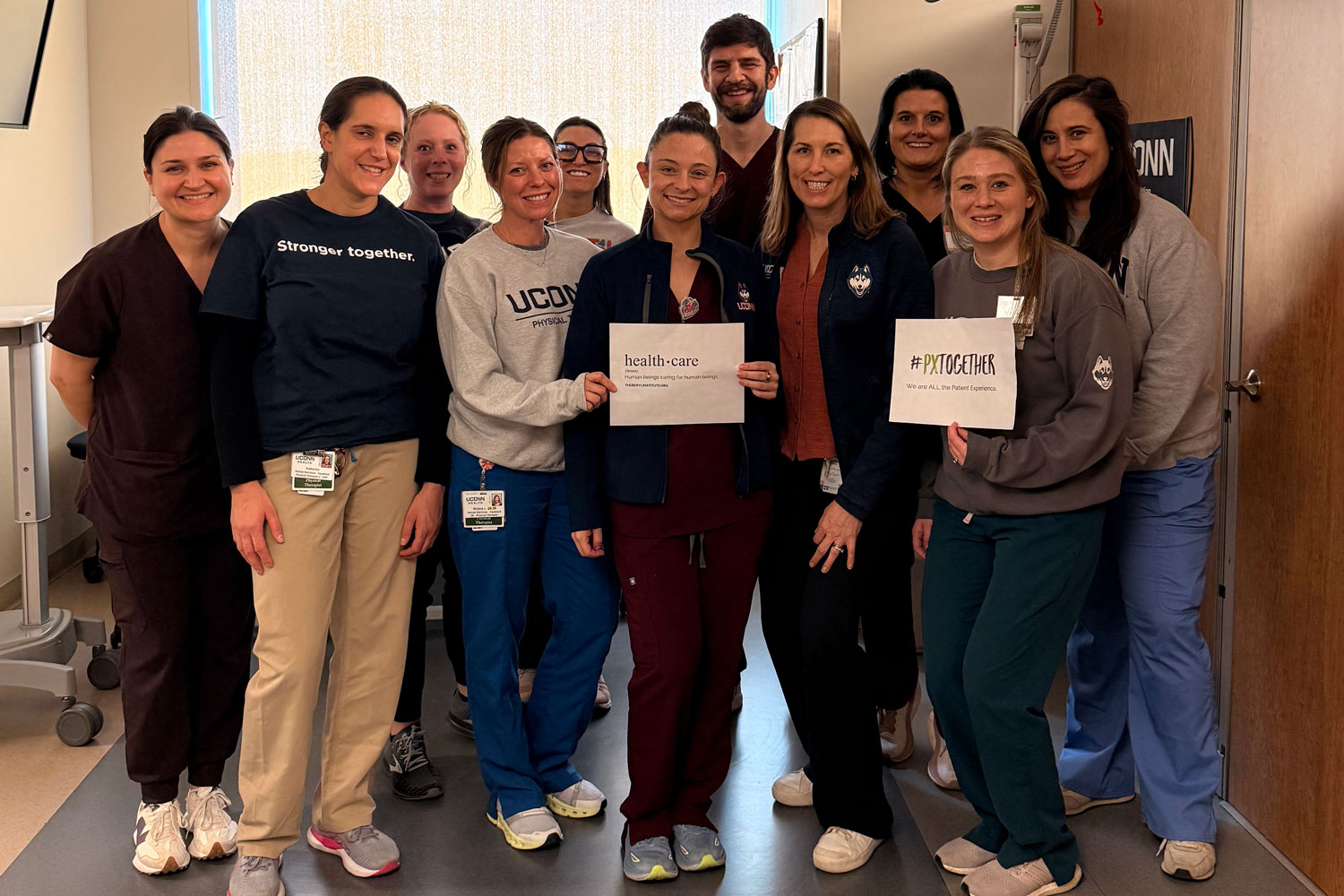 group portrait of 11 indoors, some holding signs related to Patient Experience Week