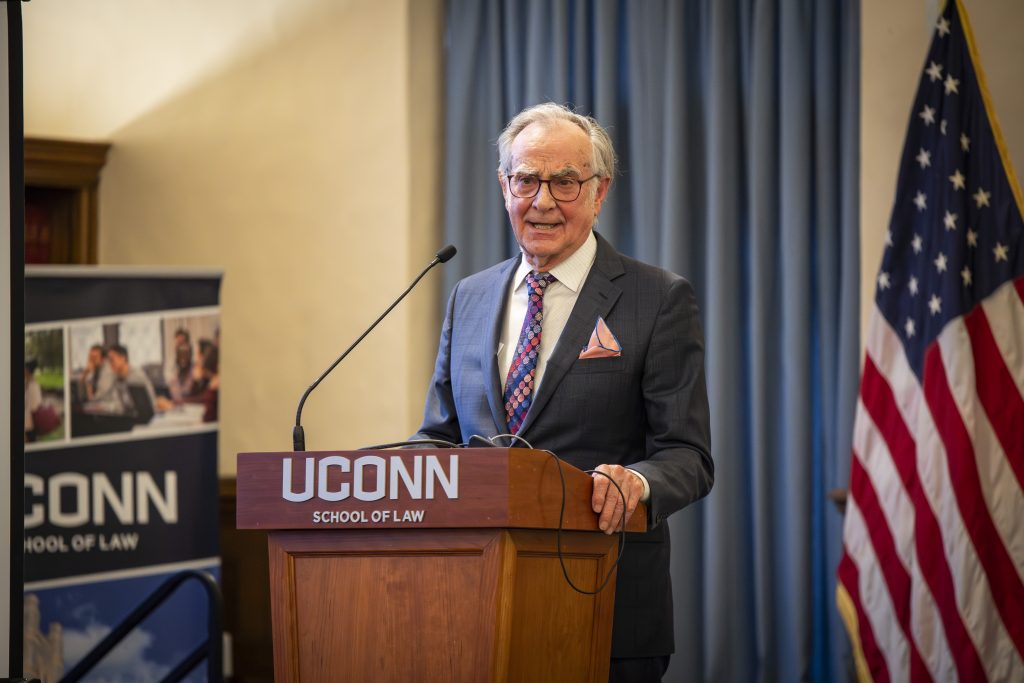 A man in a suit makes remarks from a podium.
