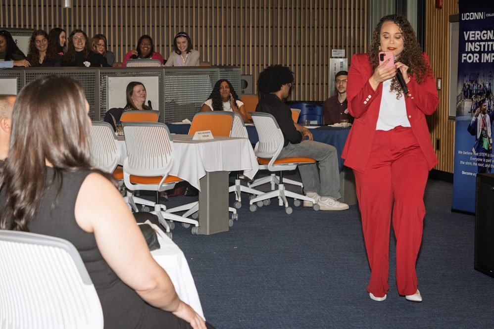 A woman sings in front of a captive audience in a lecture hall.