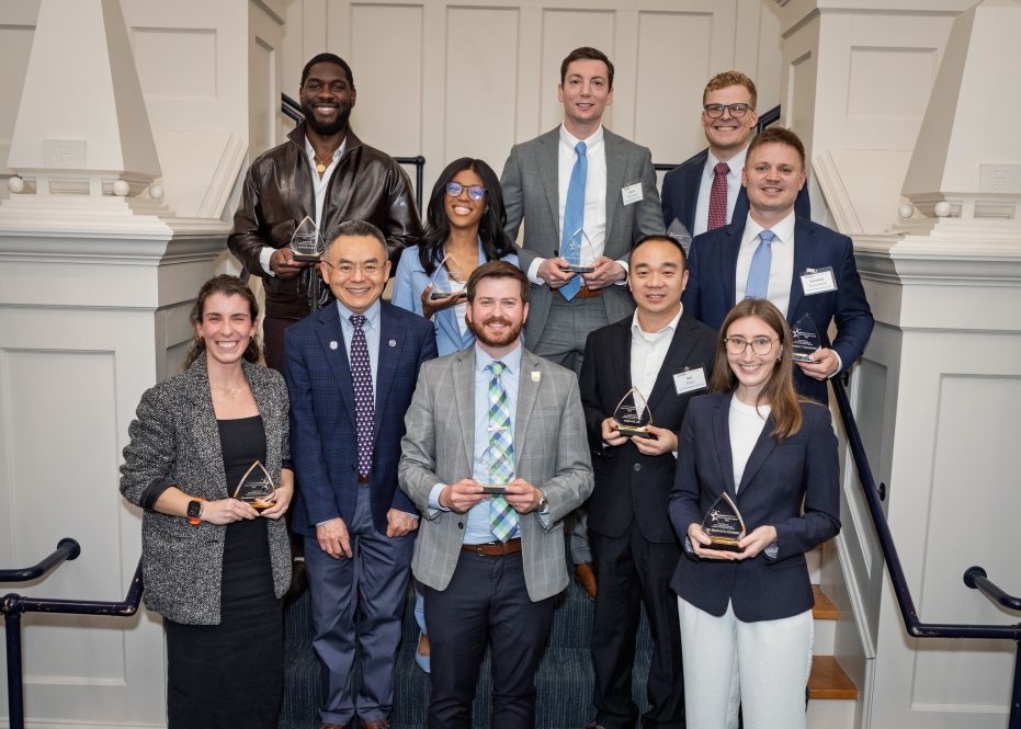 Group of UConn College of Engineering award recipients and faculty posing on a staircase holding awards.