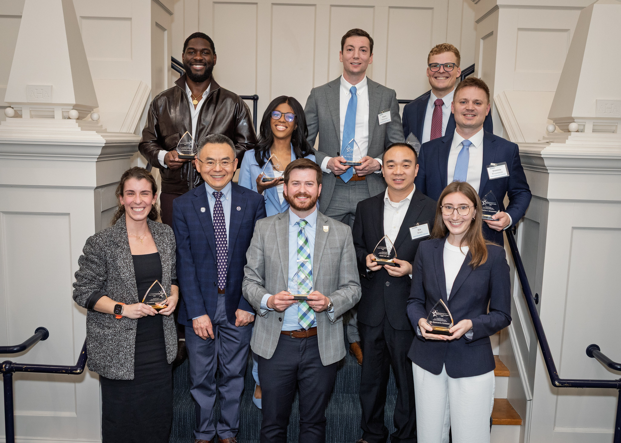 Group of UConn College of Engineering award recipients and faculty posing on a staircase holding awards.