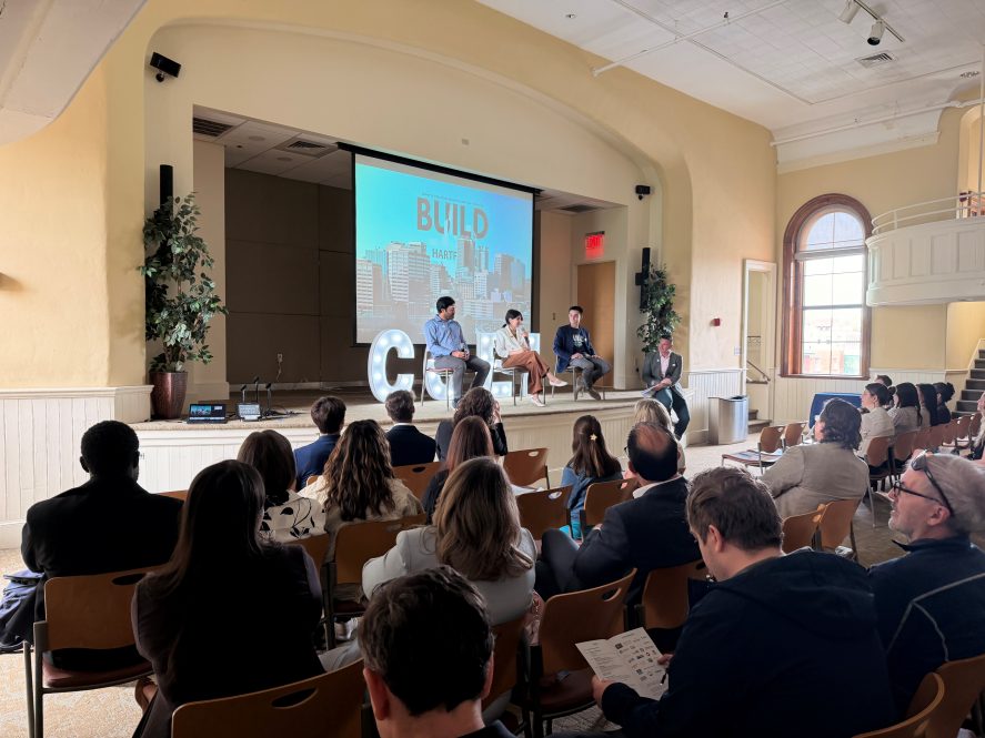Three people on stage presenting to a crowd