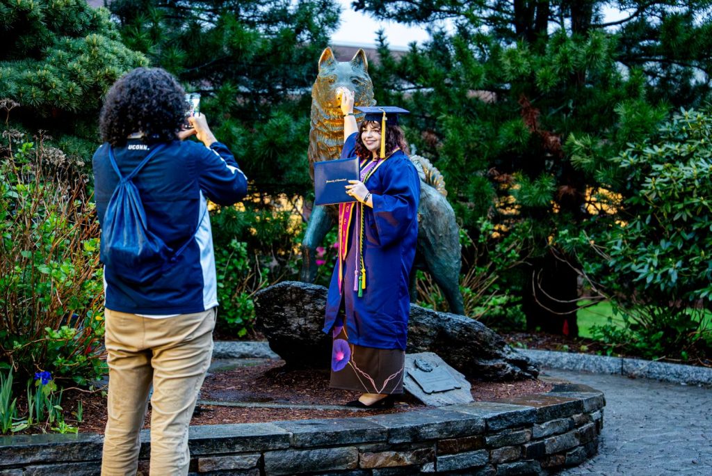 CAHNR graduate rubs the Husky statue after commencement